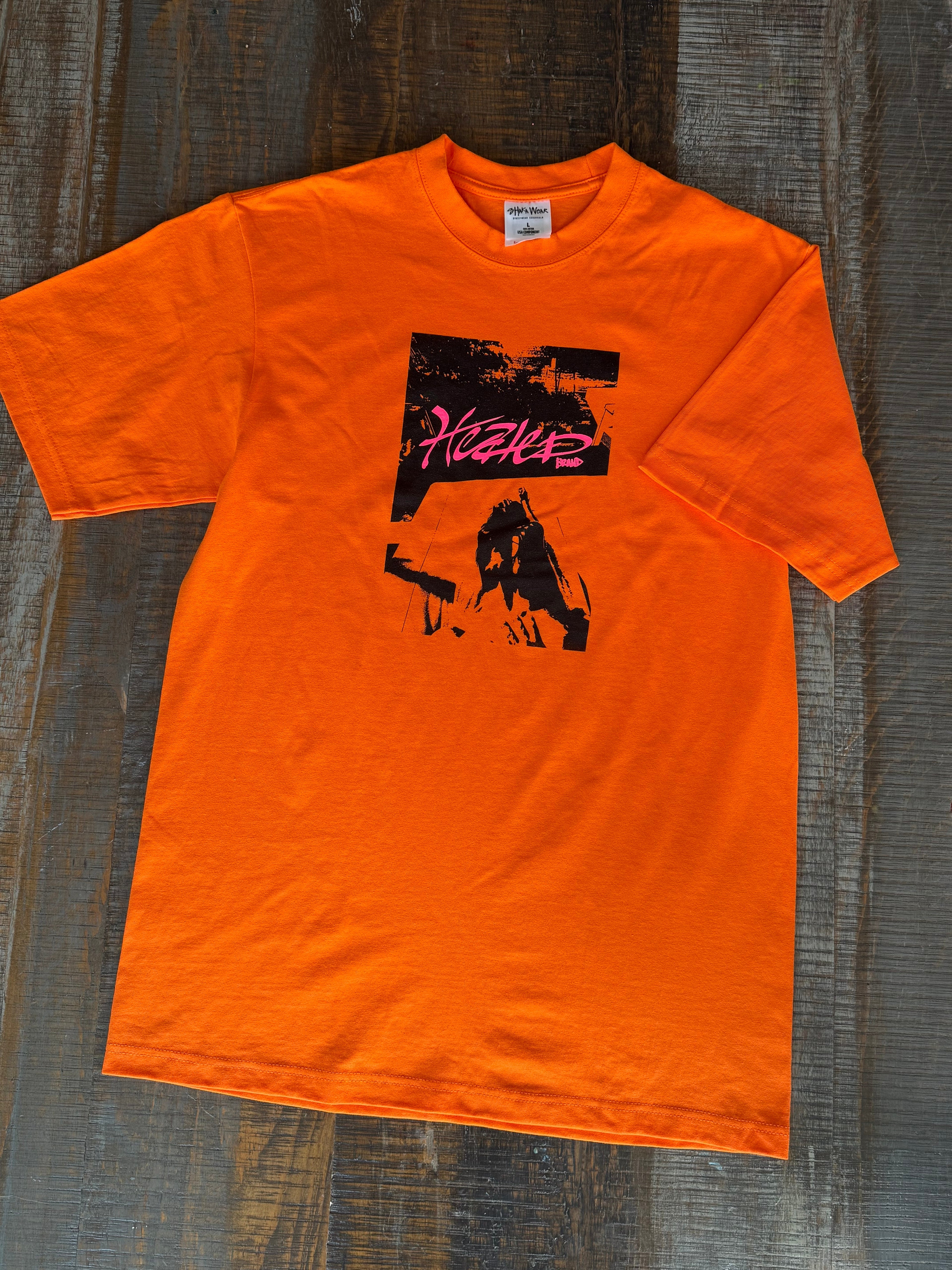 Orange t-shirt with graphic design on a wooden surface