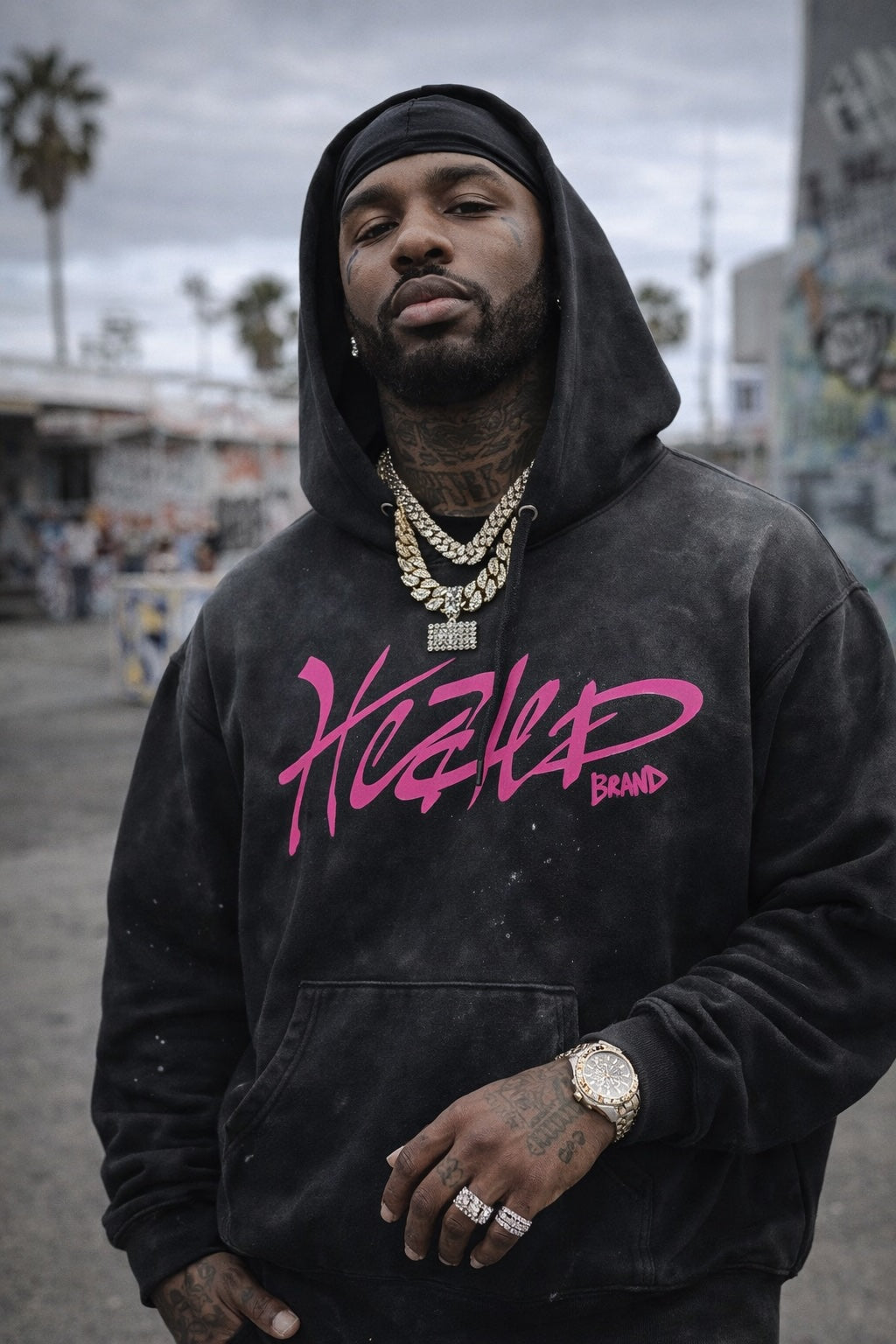 Man wearing a black hoodie with pink text, standing outdoors.